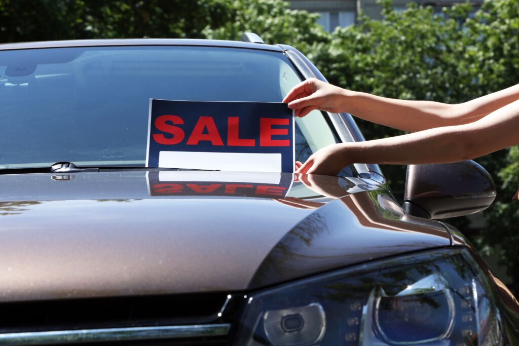 For sale sign on car showcasing sell car before going bankrupt