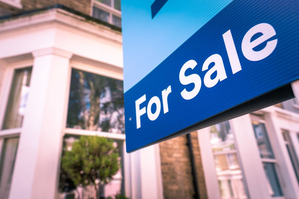 House on English street with for sale sign depicting selling house in bankruptcy