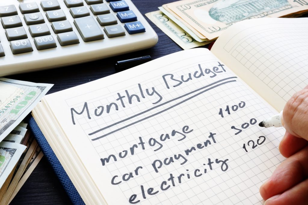 Writing living expenses on page depicting calculating an income payment agreement when living in a different country.