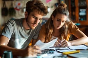 Young couple calculating monthly expenses to showcase how a partner is affected by bankruptcy