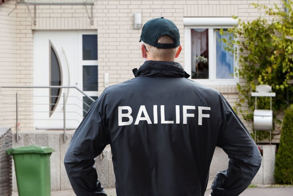 Does bailiff action stop when you go bankrupt View of Bailiff standing at house entrance showcasing how to stop a bailiff by going bankrupt.