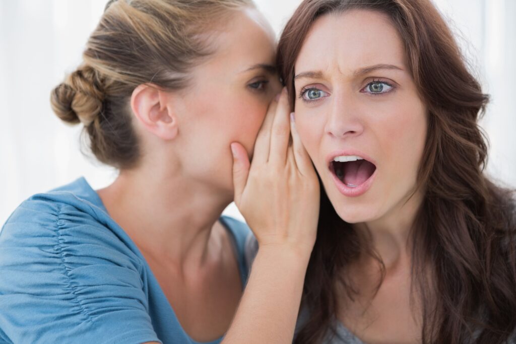 Woman being told a secret by her friend showcasing who will find out you are bankrupt