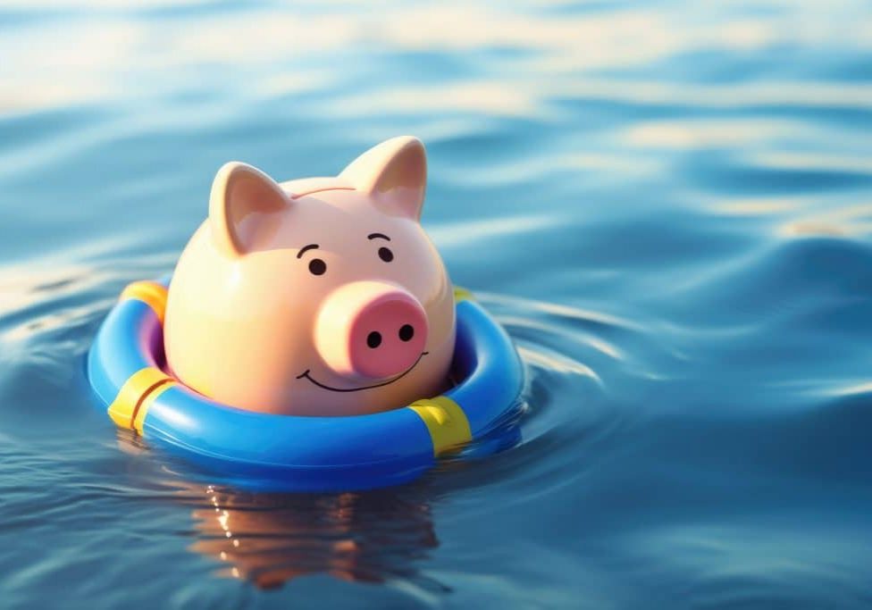 Piggy bank floating in water with coins. Losing savings. Unstable economy, recession concept.